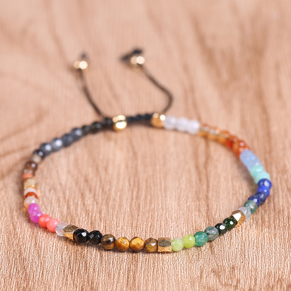 Seven chakras colored stones bracelet close-up, multicolor beads and dangling cord tips