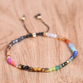 Seven chakras colored stones bracelet close-up, multicolor beads and dangling cord tips